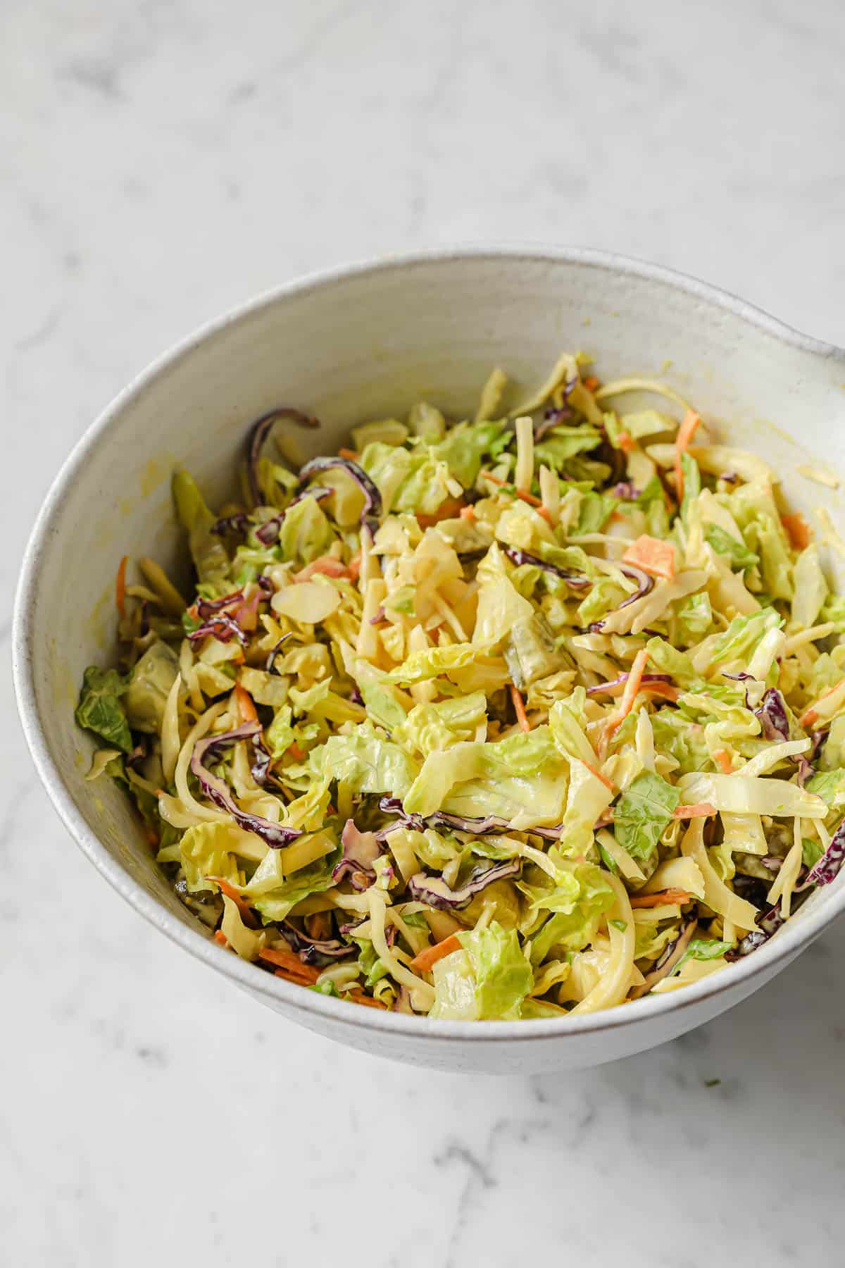 fresh chopped lettuce and coleslaw mix being tossed in homemade sweet mustard dressing
