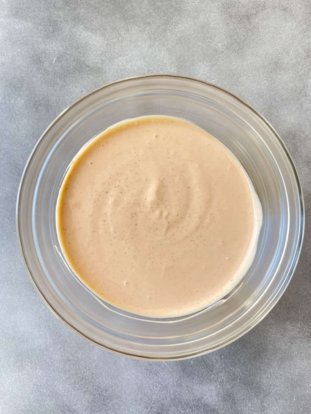 A bowl of homemade burger sauce on a concrete background