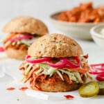 barbecue pulled pork sandwich with keto buns, barbecue pork, broccoli slaw, and pickled red onions
