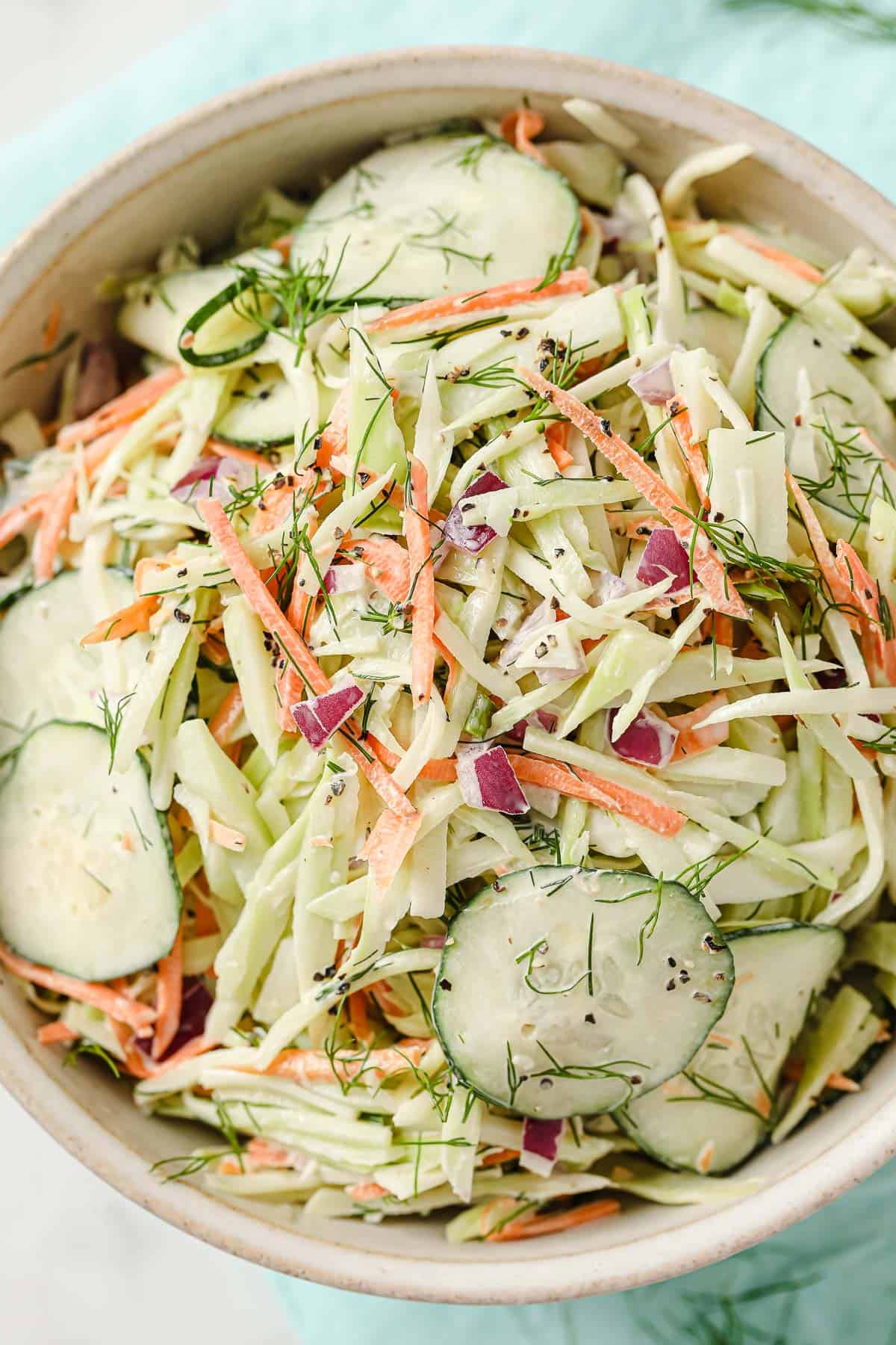 a bowl of whole30 coleslaw with broccoli slaw, cucumber, mayo, red onion, dill, garlic, salt and pepper