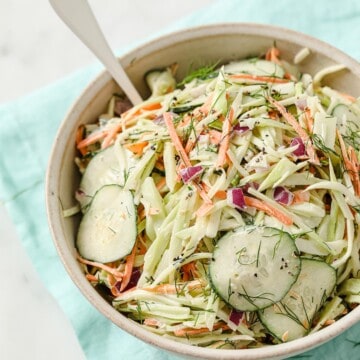 a bowl of paleo coleslaw with broccoli slaw, cucumber, mayo, red onion, dill, garlic, salt and pepper