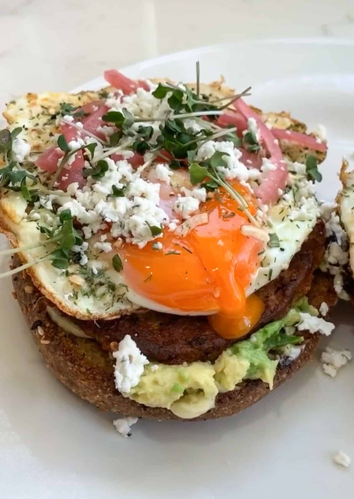open face breakfast sandwich with egg, goat cheese, pickled red onion, microgreens and avocado 