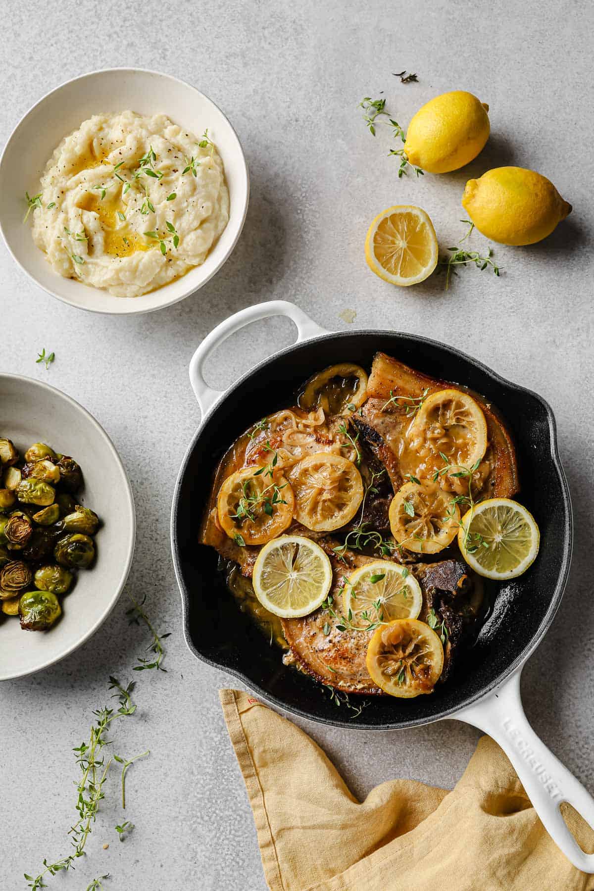 pan-seared pork chops with a lemon thyme pan sauce, served with cauliflower mash and brussels sprouts