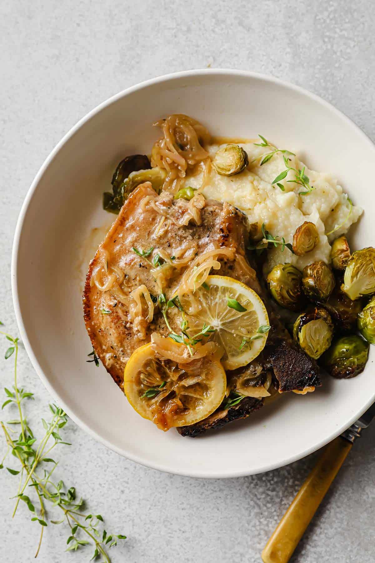 Lemon Thyme Pork Chops plated with mashed cauliflower and roasted brussels sprouts