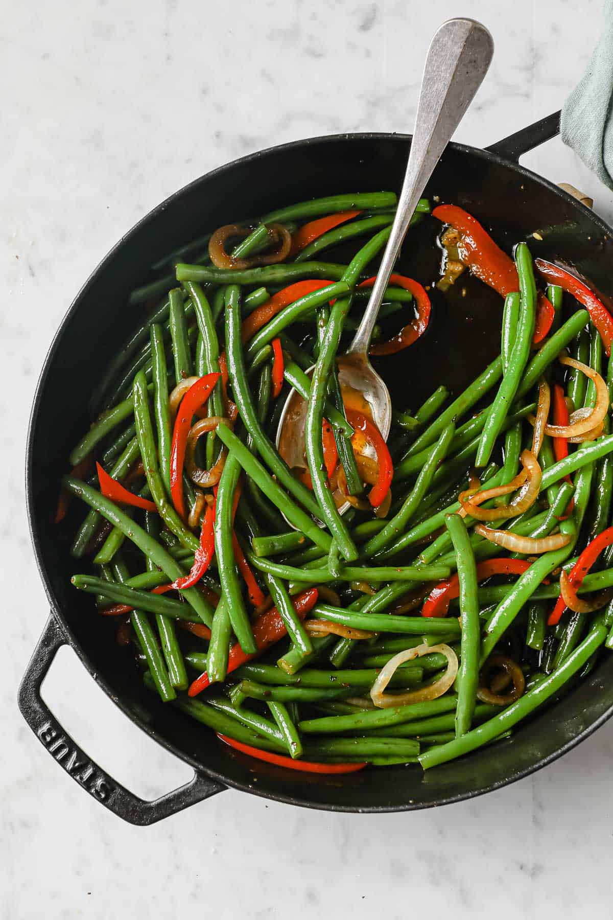 cast iron skillet with Sweet and Spicy Green Beans with peppers, onions, garlic, soy sauce, and brown sugar