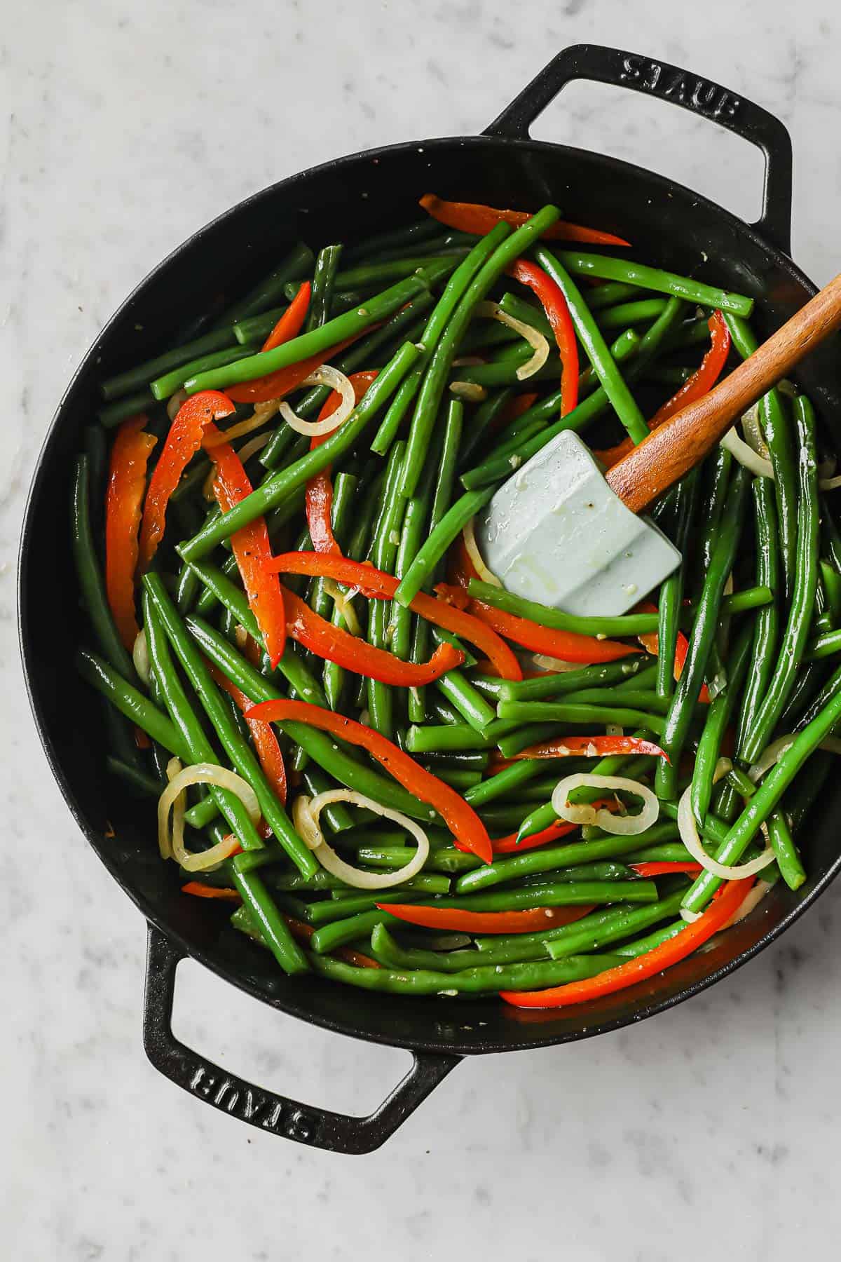 cast iron skillet with Sweet and Spicy Green Beans with peppers, onions, garlic, soy sauce, and brown sugar