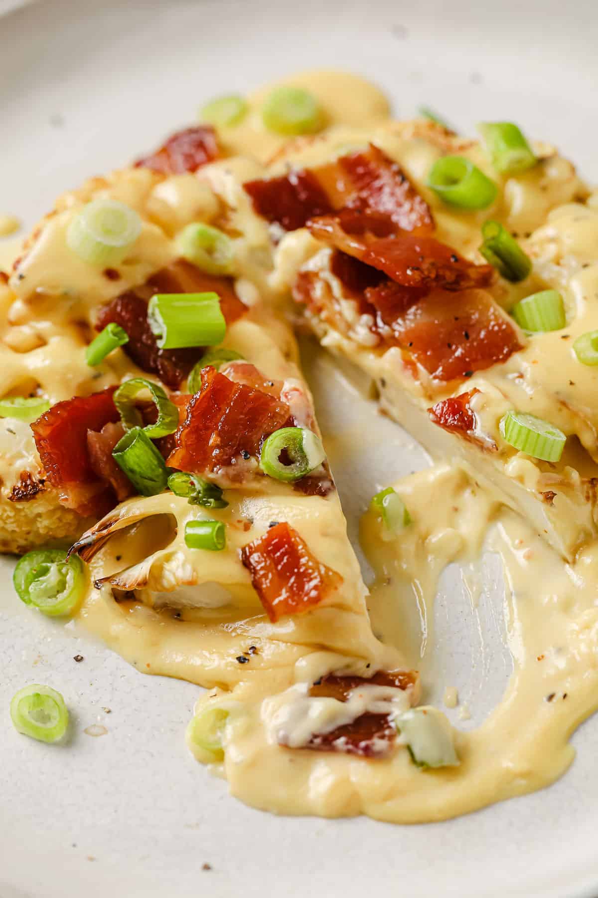 oven roasted cauliflower steaks, topped with cheese sauce, bacon, and green onions