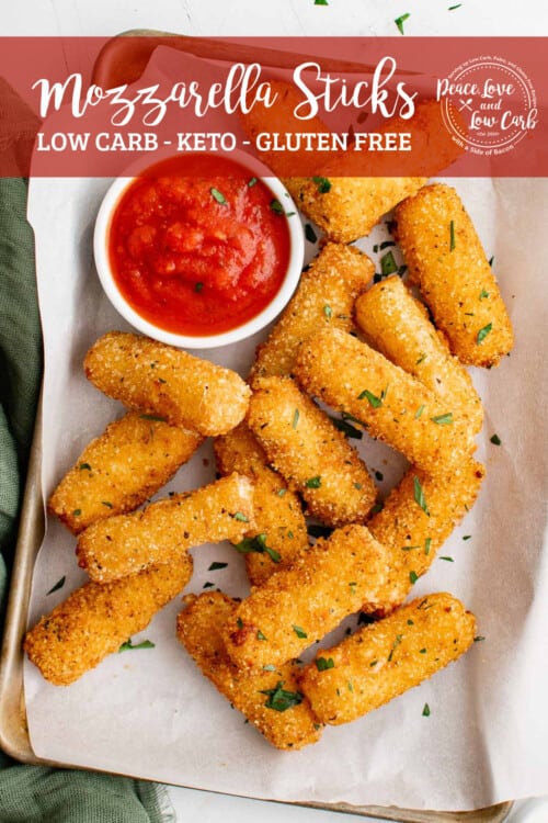 a serving tray, lined with parchment paper, filled with low carb mozzarella sticks and marinara sauce