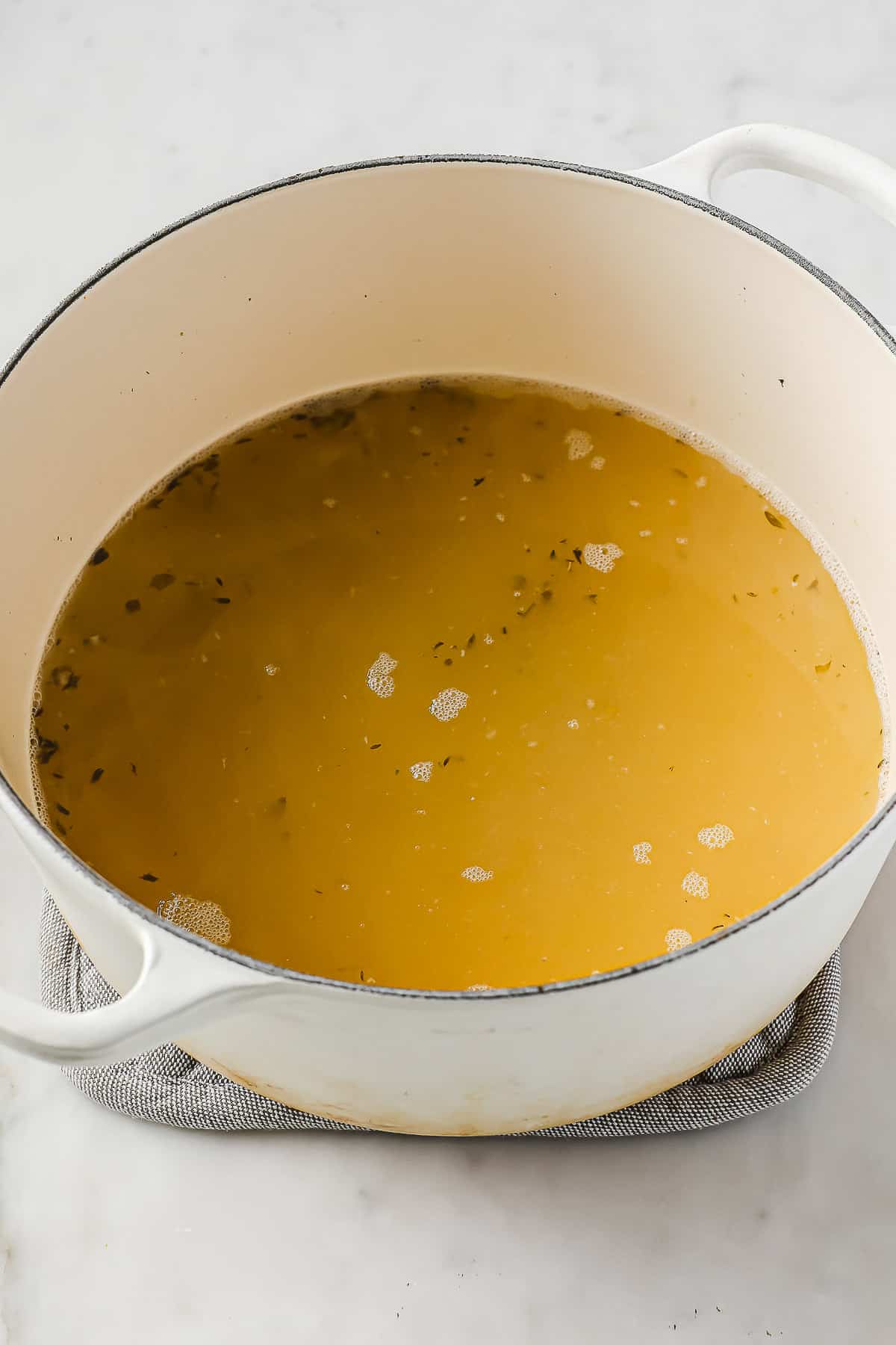 A dutch oven filled with chicken stock and seasonings
