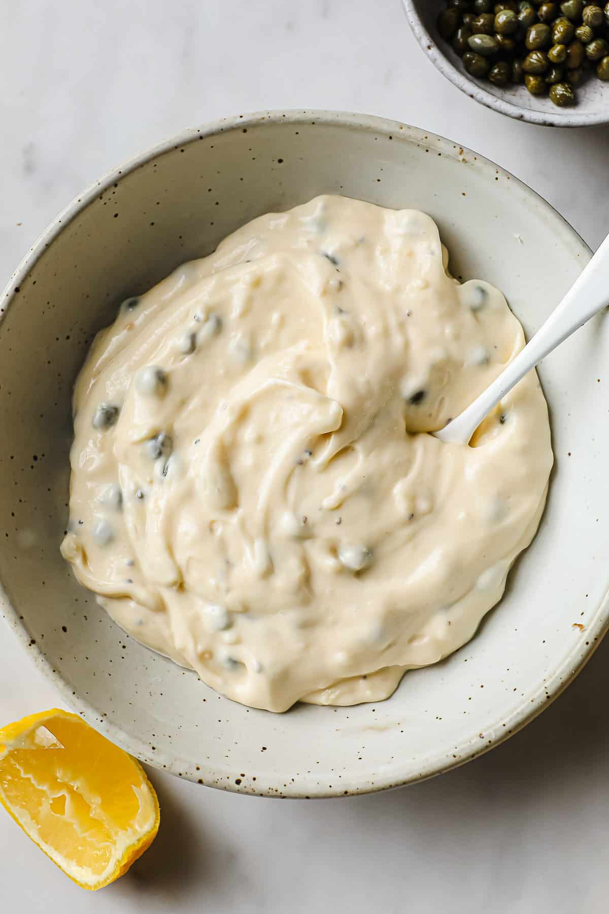A mixing bowl with mayo, capers, lemon juice, garlic, salt, dijon, and capers