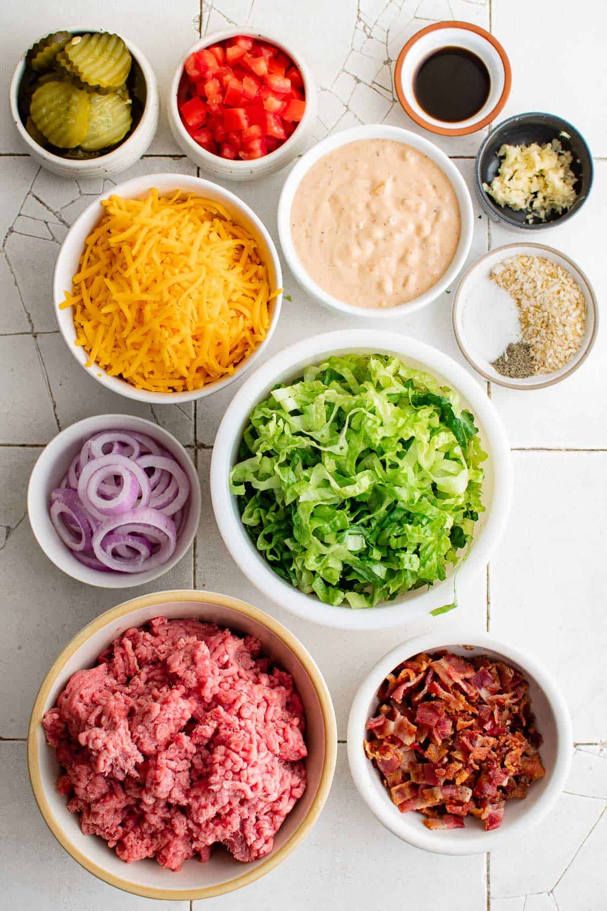 individual bowls with ground beef, lettuce, cheese, tomatoes, pickles, red onions, burger sauce