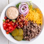 a salad made with ground beef, cheese, bacon, onion, tomatoes, pickles and burger sauce.