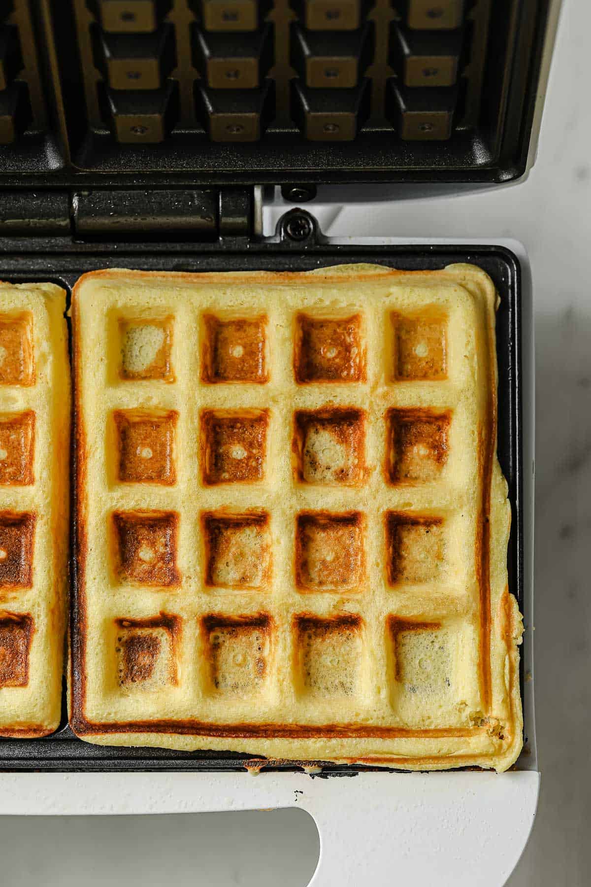 A waffle iron with keto waffle batter in it