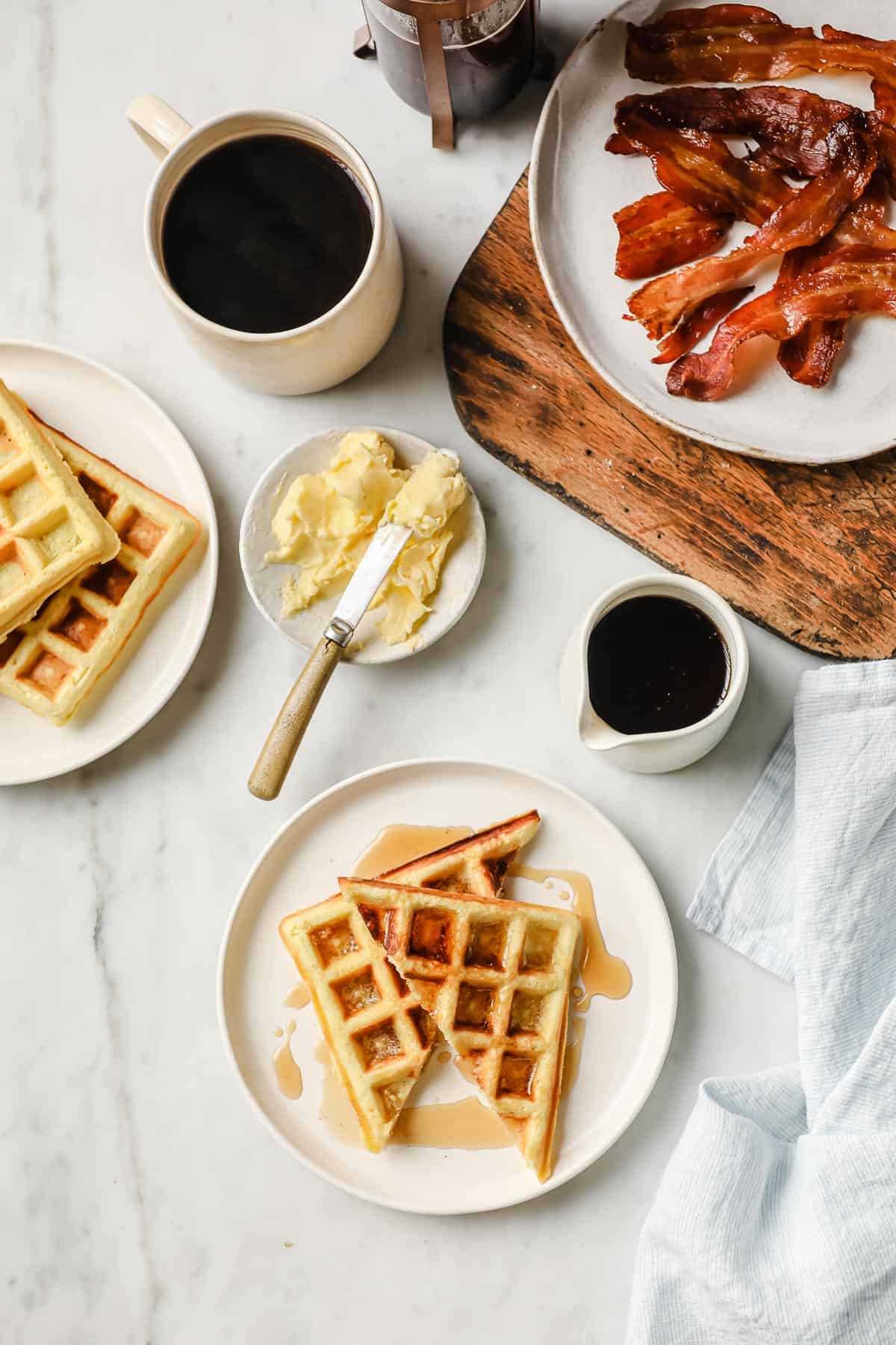 coconut flour waffles on a white plate, with syrup and bacon on the side