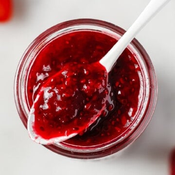 a mason jar full of low carb jam, served with a white spoon and fresh berries next to it