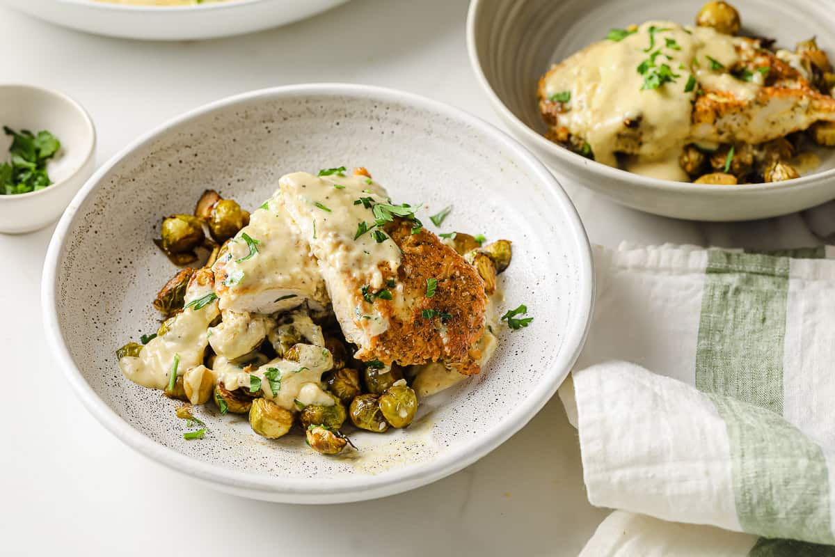 a ceramic bowl with crispy Brussels sprouts topped with crispy chicken and lemon cream sauce