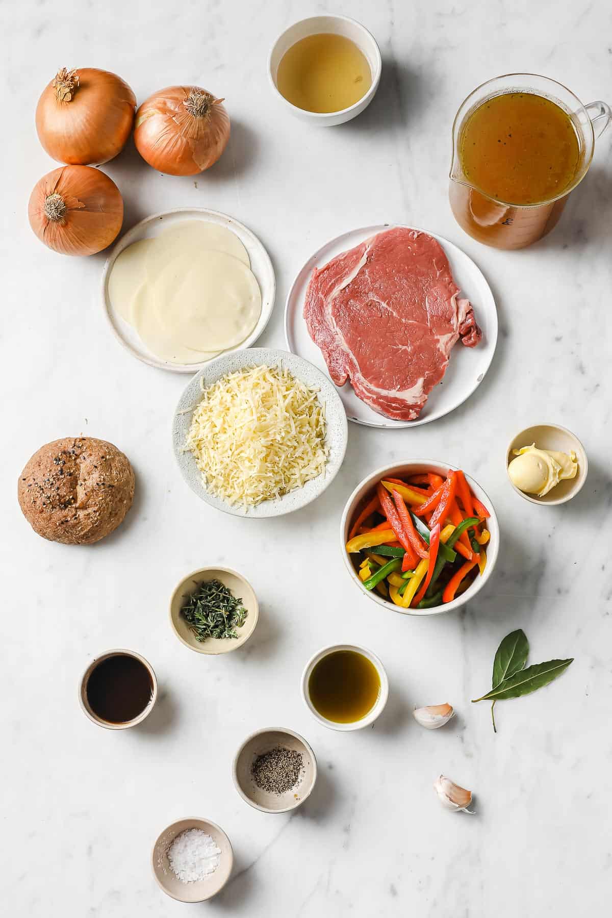 ingredients to make keto French onion soup - ribeye, onion, peppers, garlic, cheese, broth, herbs, spices and bread
