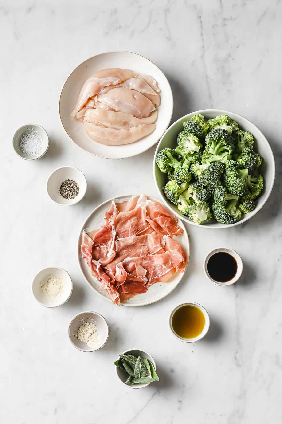 ingredients set out in individual bowls - chicken, prosciutto, broccoli, balsamic, olive oil, and seasonings.