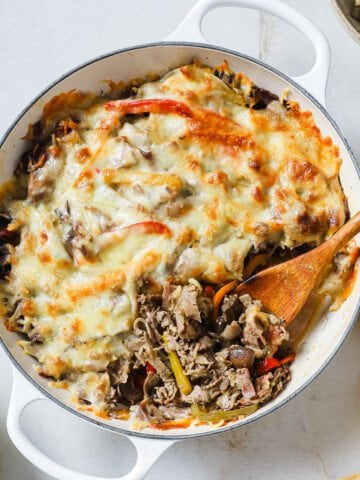 a cast iron skillet with a Philly cheesesteak casserole in it.