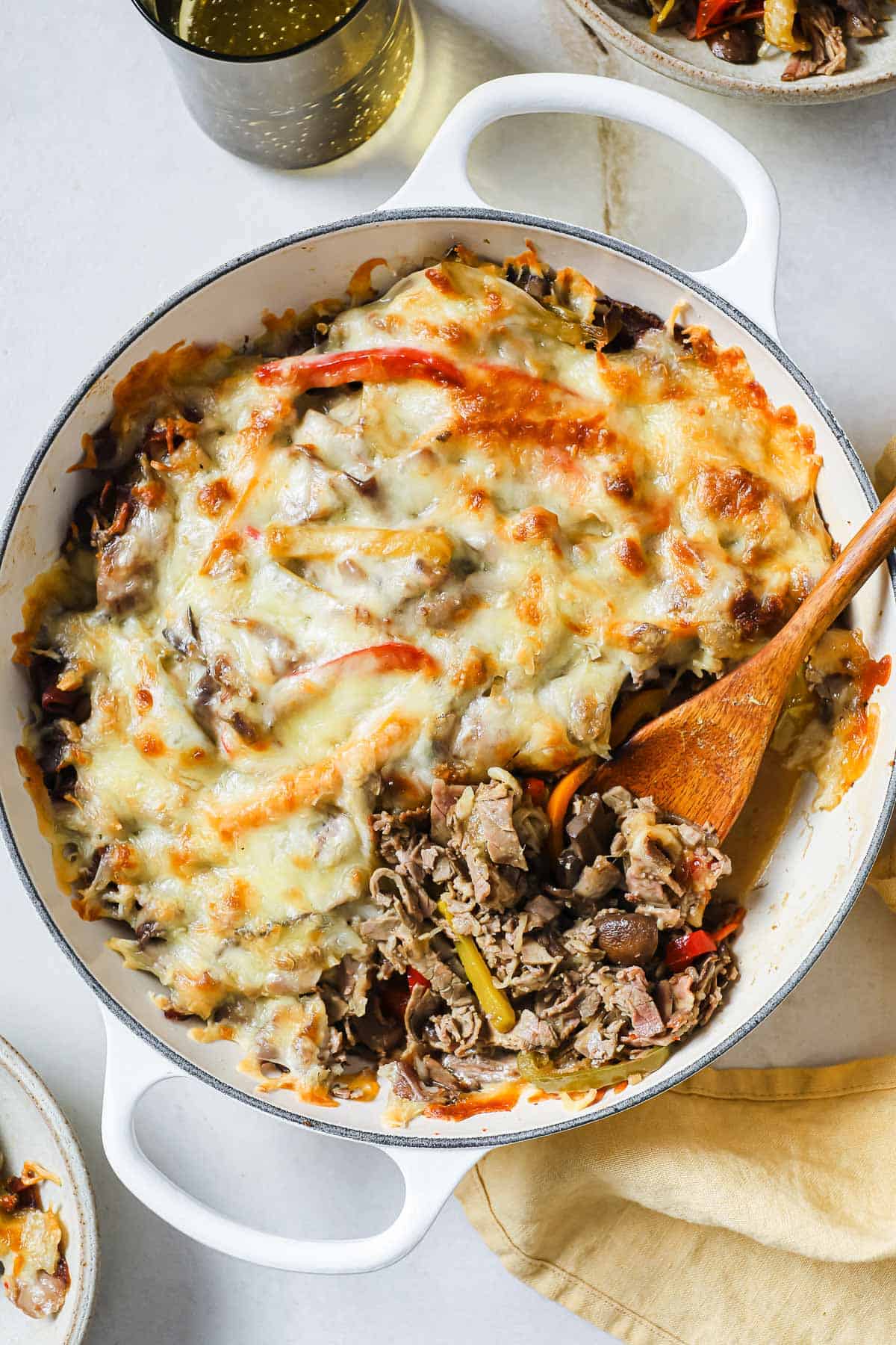 a cast iron skillet full of a casserole with meat, cheese, and vegetables.