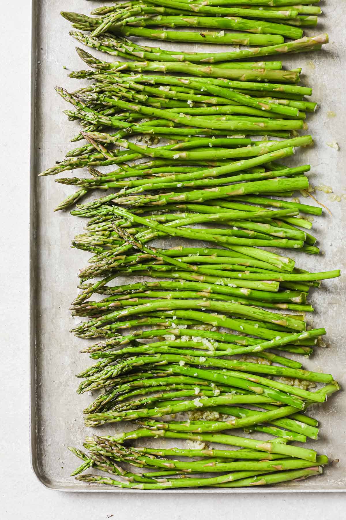 a baking sheet lined with parchment paper, full of roasted asparagus, and garlic.