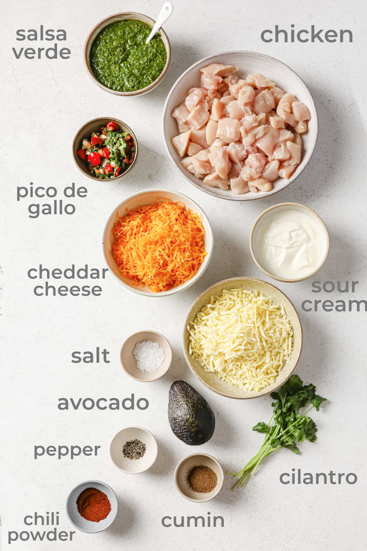 Ingredients all laid out to make a Mexican chicken casserole - chicken, cheese, salsa, pico de Gallo, avocado, cilantro and spices.
