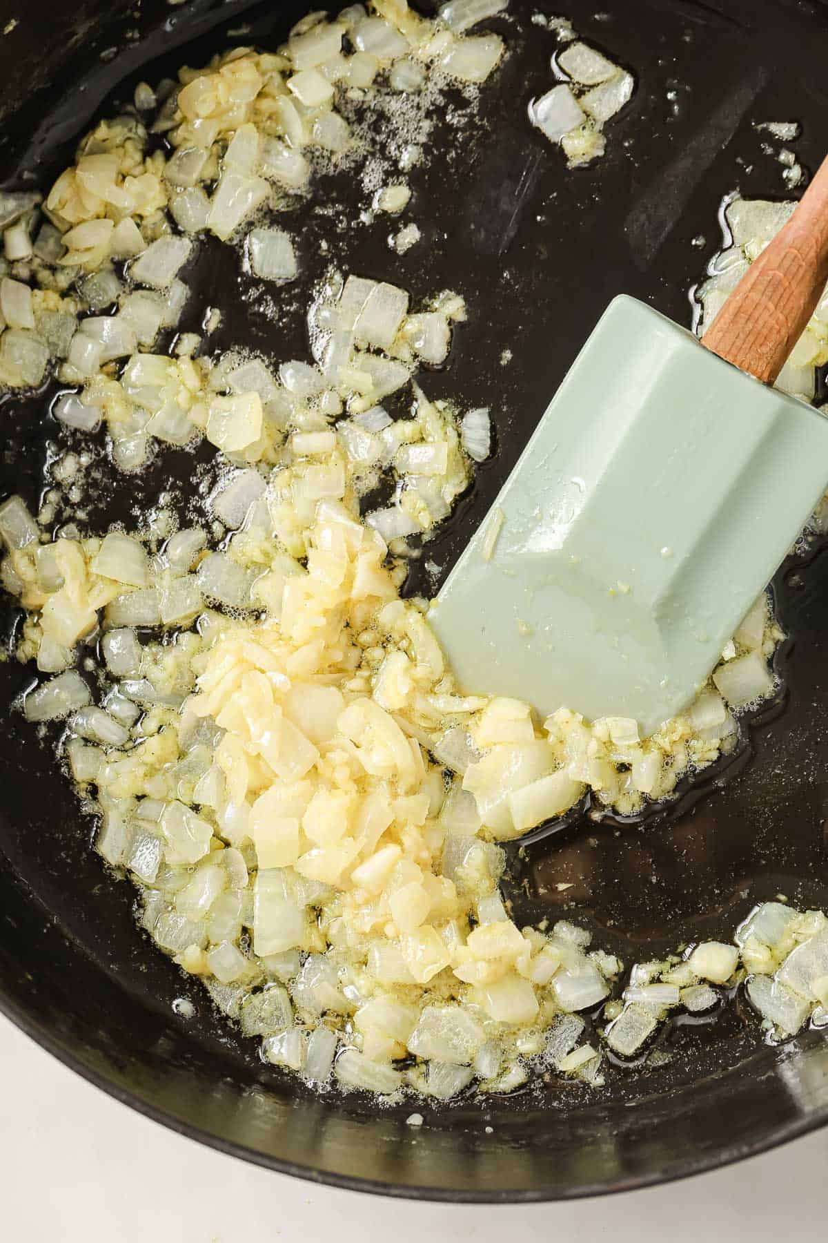 A cast iron skillet with chopped onions sautéing in butter.
