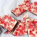Peppermint bark made with white chocolate and dark chocolate, peppermint candies, broken up and served on white parchment paper.