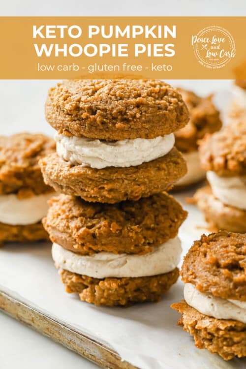 a dish lined with parchment paper and filled with pumpkin spice whoopie pies filled with cream cheese frosting.