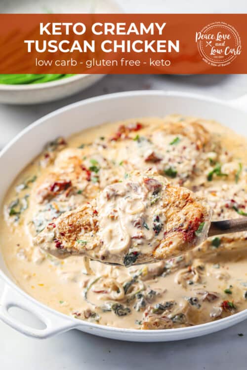 A white ceramic skillet full of a creamy chicken dish with chicken breasts, spinach, sun-dried tomatoes, garlic, onion, parmesan cheese and heavy cream.