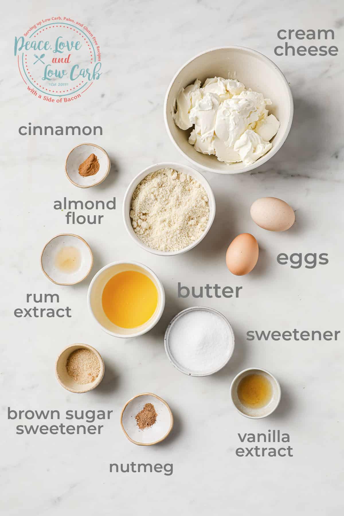 Ingredients all laid out to make mini eggnog cheesecakes - cream cheese, eggs, almond flour, butter, sweetener, spices. 
