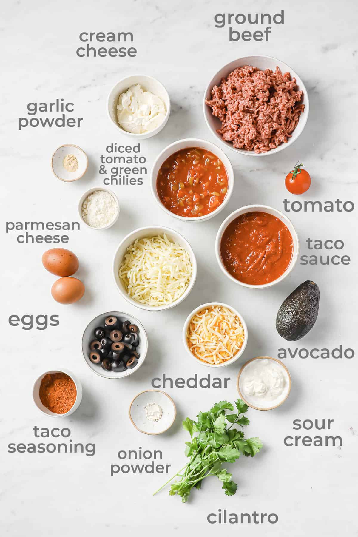 Ingredients all laid out to make a low carb lasagna - ground beef, cheeses, tomatoes, taco sauce, avocado, cilantro.